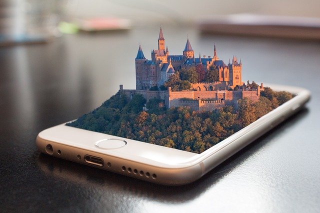 Ein Smartphone, aus dessen Display eine Burg in einem Wald wächst.